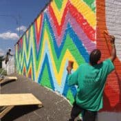 Artists working on a mural with two walls