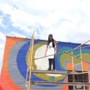 Artist on a scaffold with mural in background