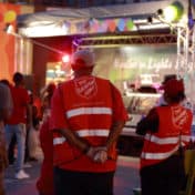 Volunteers with Salvation Army jackets watching the stage