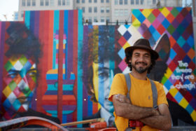 Artist Eduardo Kobra standing in front of the Bob Dylan mural