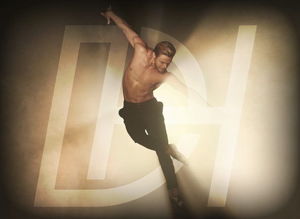Derek Hough dancing without shirt, with bright spotlight behind