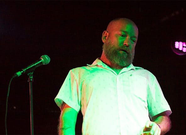 Kyle Kinane in front of microphone looking down