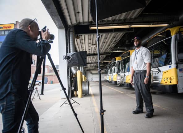 Photographer taking a photo of a transportation worker in front of buses