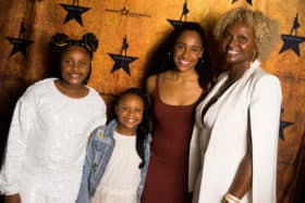 Hennepin Theatre Trust board member poses with her granddaughters and a Hamilton cast member 