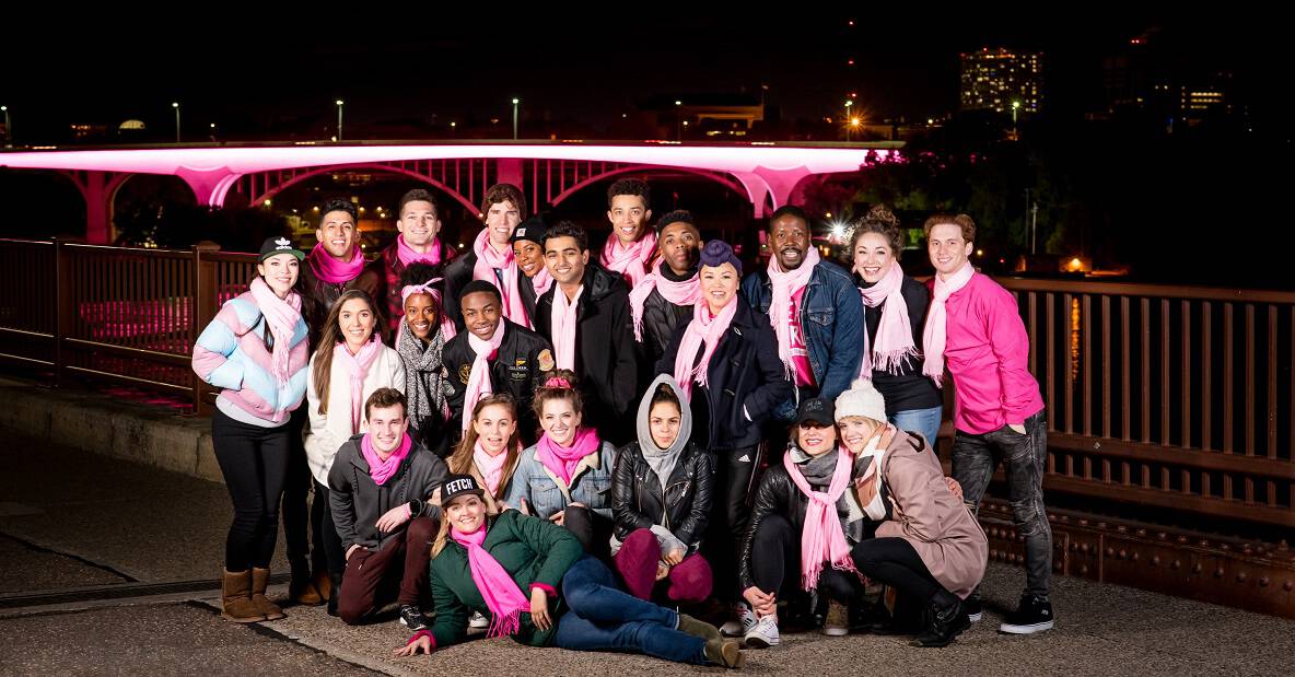 The cast of Mean Girls in Minneapolis posed in front of the pink-lit I-35W bridge in honor of Breast Cancer Awareness month.