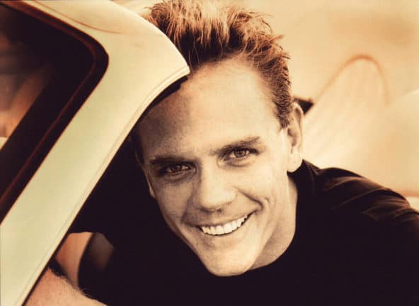 Christopher Titus sitting in a convertible, smiling; sepia tone
