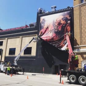 Crews install a portrait banner as part of the "It's the People" public art project