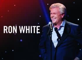 Ron White smiling while talking into a microphone