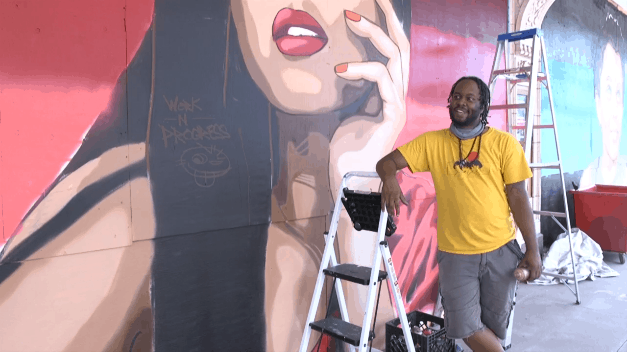 Artist Reggie LeFlore in front of his mural on the historic state Theatre