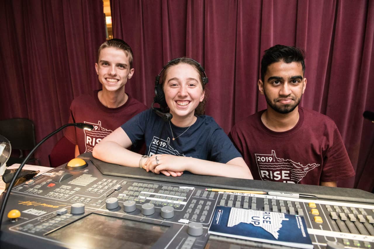 A group of three students behind a sound board
