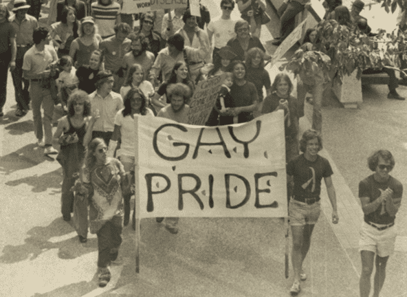 Vintage photo of the Minneapolis Gay Pride Parade. A group of people hold a large banner with the words "Gay Pride" on it.