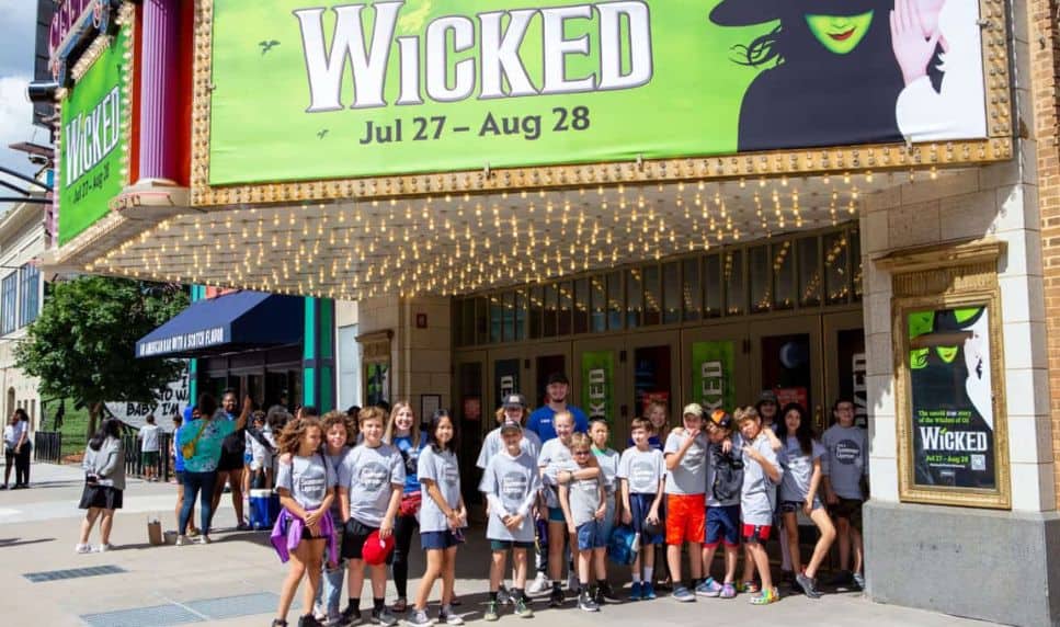 A group of smiling kids underneath the Wicked marquee at the Orpheum Theatre.