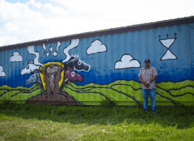 Ray "Rockboy" Janis and his mural of a green landscape and four horse heads