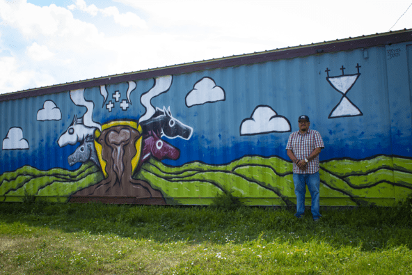 Ray "Rockboy" Janis and his mural of a green landscape and four horse heads