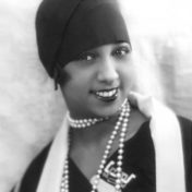 Woman wearing hair wrap and strings of pearls, poses and smiles. Photo Credit: Public Domain