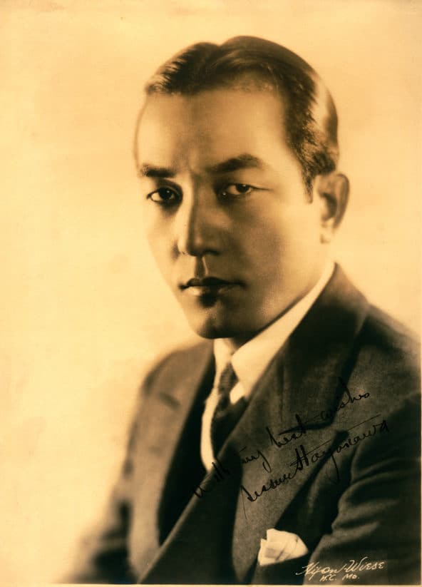 Man seated in suit and tie poses facing left with a calm face. Photo Credit: Hennepin County Library