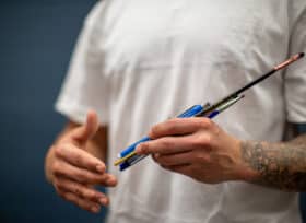 A person in a white t-shirt holding pain brushes