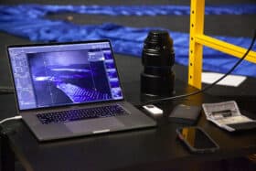 A macbook pro and a camera lens sit on a table