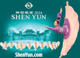 Shen Yun 2024. ShenYun.com. Woman with flowing long dress and with arms extended, raises one foot vertical behind her; Many dancers in row strike a uniform pose in the foreground before a temple.