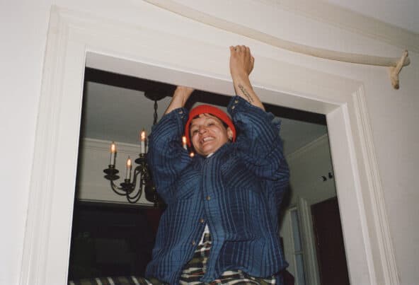 image of Adrianne Lenker hanging from a doorframe