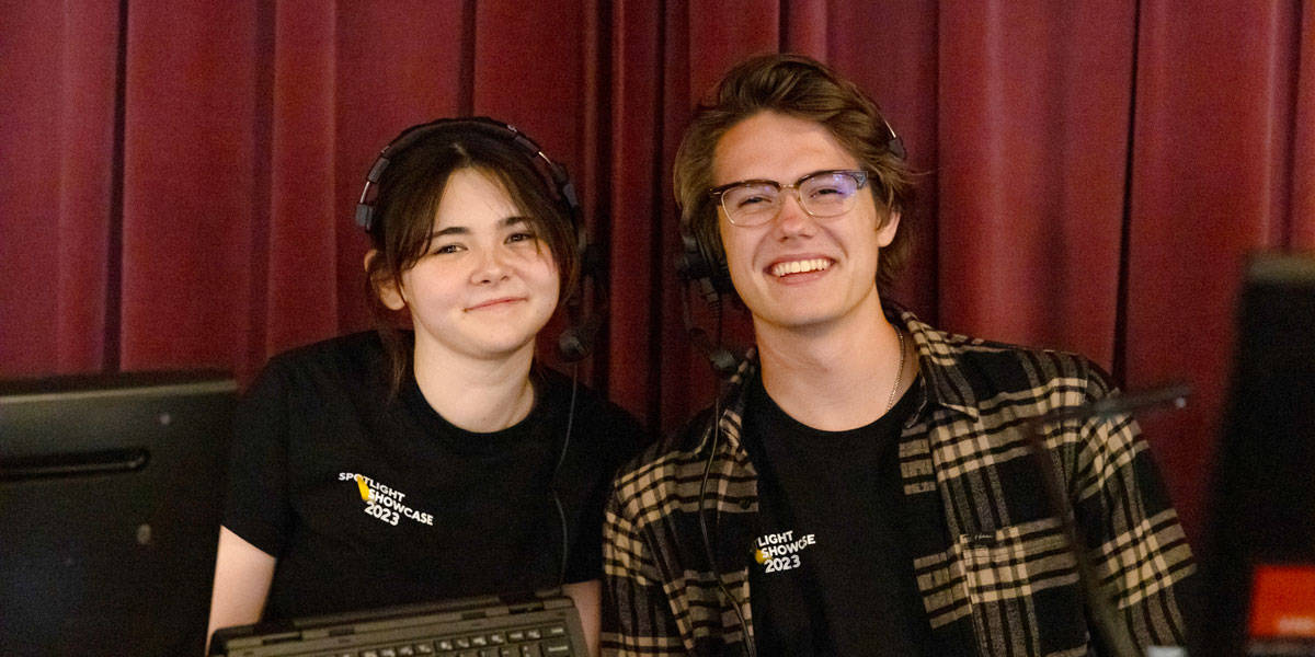 two students at spotlight showcase wearing headsets and smiling